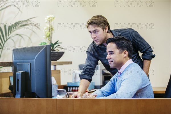 Businessmen working at computer in office lobby