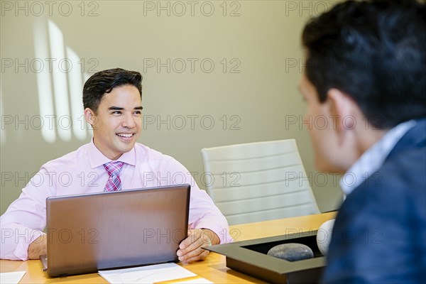 Mixed race businessmen talking in office meeting