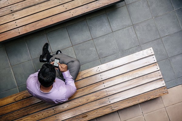 Overhead view of mixed race businessman using cell phone in office courtyard