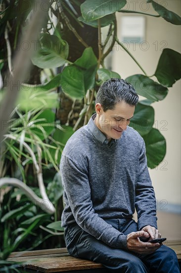 Mixed race businessman using cell phone in office courtyard