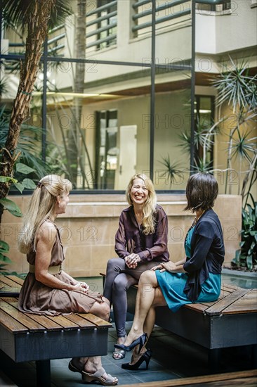 Businesswomen talking in office courtyard