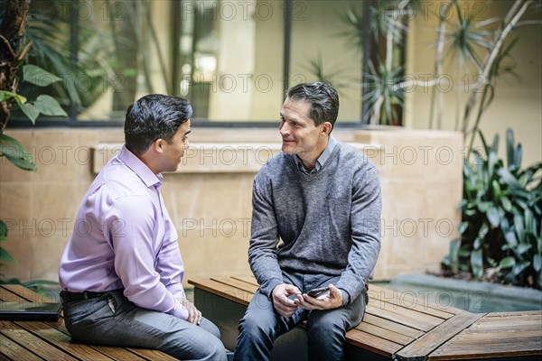 Mixed race businessmen talking in office courtyard