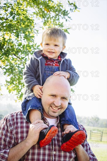 Caucasian father carrying son on shoulders