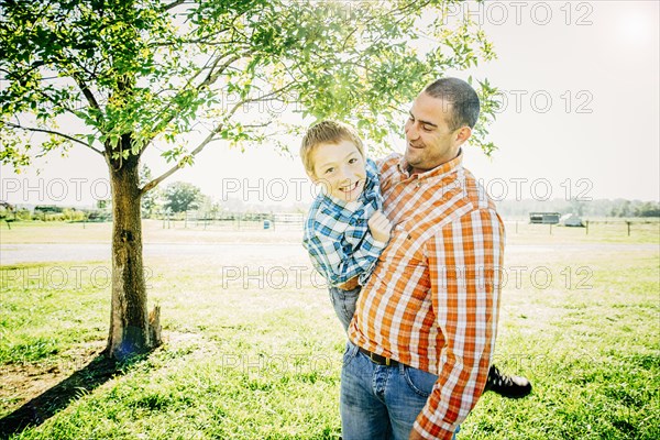 Smiling father carrying son on farm