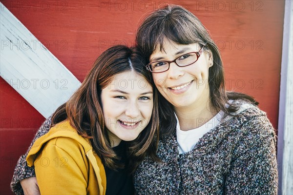 Caucasian mother and daughter smiling outside barn