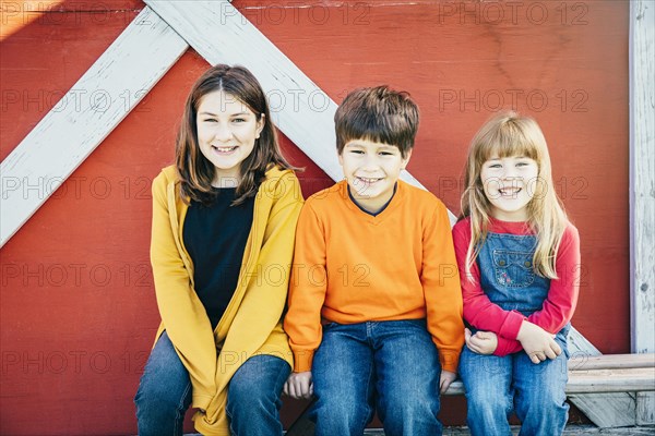 Caucasian brother and sisters smiling on farm