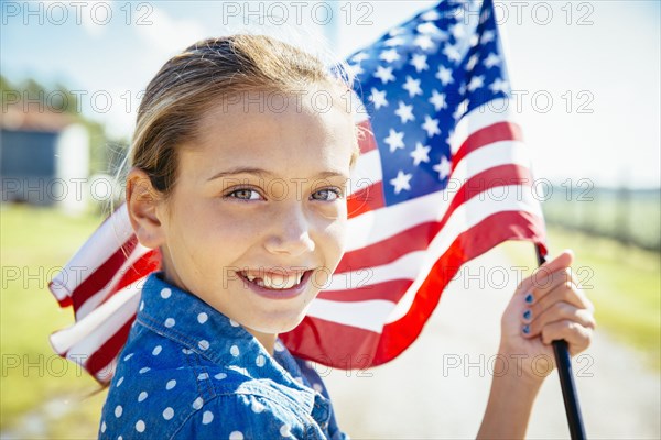 Caucasian girl waving American flag on farm