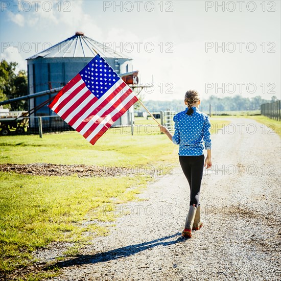 Caucasian girl waving American flag on farm