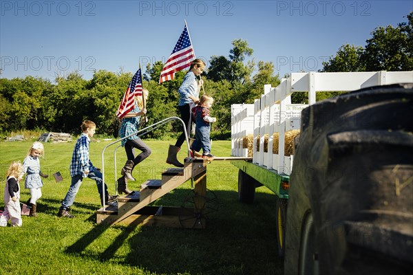 Caucasian children climbing stairs to hay ride on farm