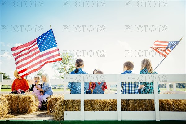 Caucasian children waving American flags on hay ride