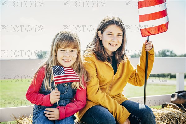 Caucasian girls waving American flags on hay ride