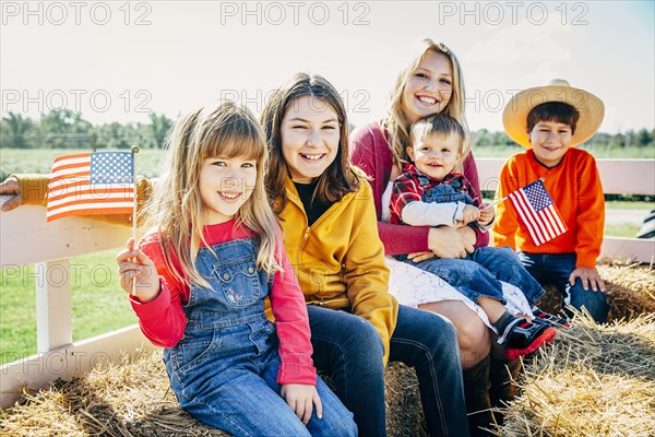 Caucasian mother and children waving American flags on hay ride