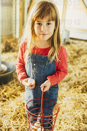 Caucasian girl collecting eggs in barn