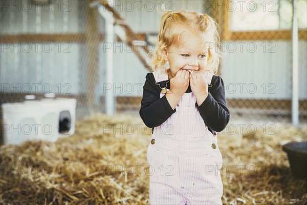 Caucasian girl biting fingers in barn