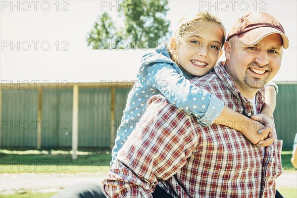 Caucasian father carrying daughter piggyback on farm