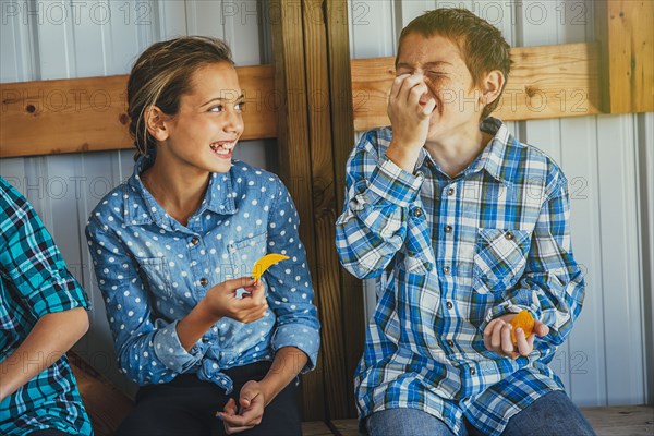 Caucasian brother and sister eating chips