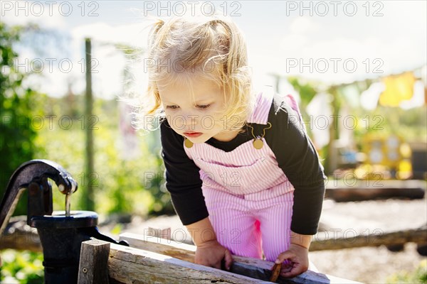 Caucasian girl peering over wooden fence
