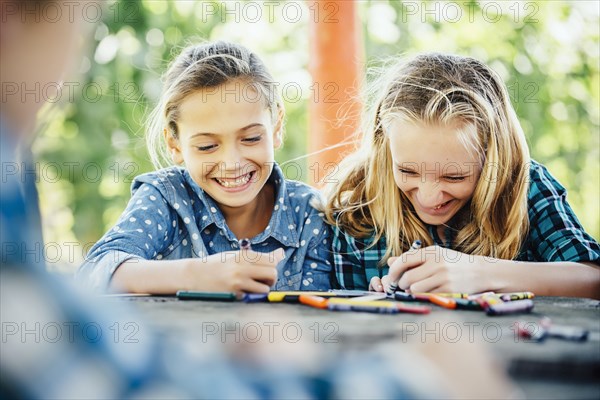 Smiling Caucasian girls coloring outdoors