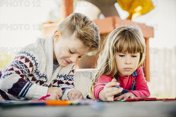 Caucasian brother and sister coloring outdoors