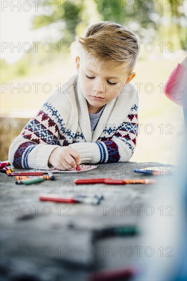 Caucasian boy coloring outdoors