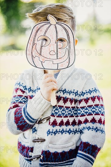 Caucasian boy holding jack-o-lantern mask