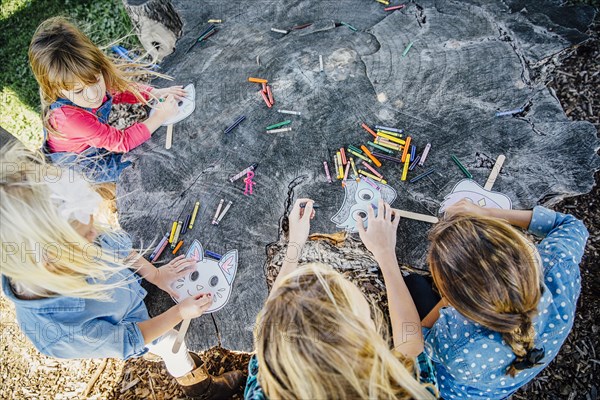 Caucasian children coloring on tree stump