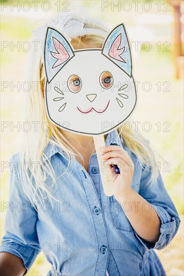 Caucasian girl holding cat mask