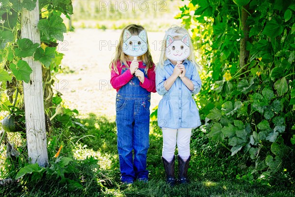 Caucasian girls holding cat mask