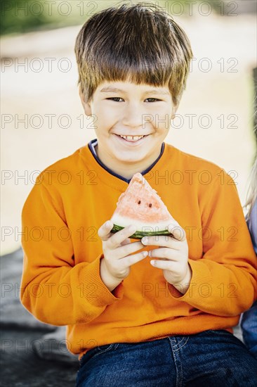 Caucasian boy eating watermelon outdoors