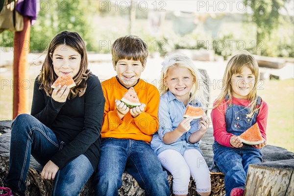 Caucasian children eating watermelon outdoors