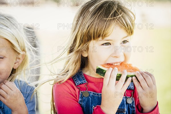 Caucasian girls eating watermelon outdoors