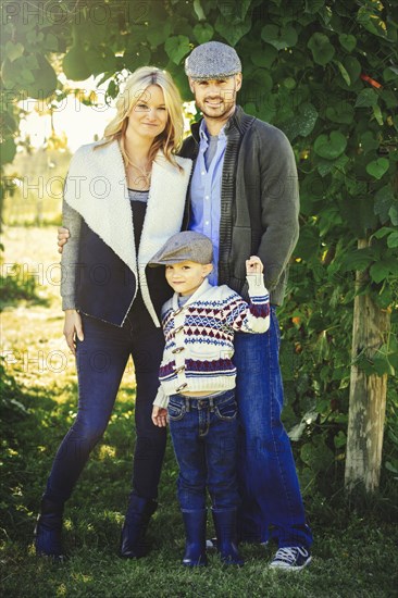 Caucasian family smiling under ivy leaves