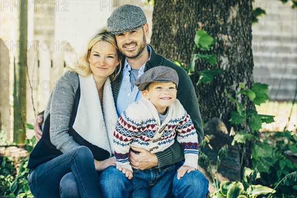 Caucasian family smiling under tree