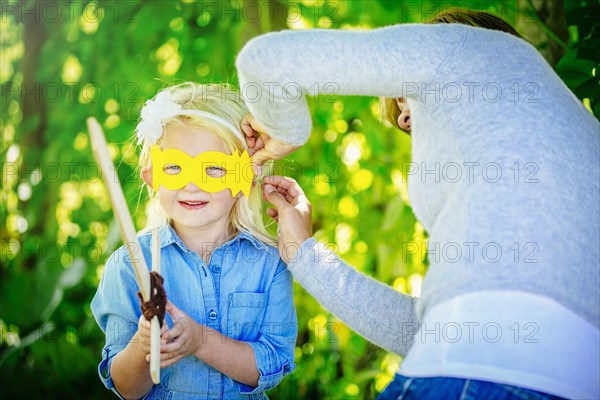 Caucasian mother tying mask on daughter