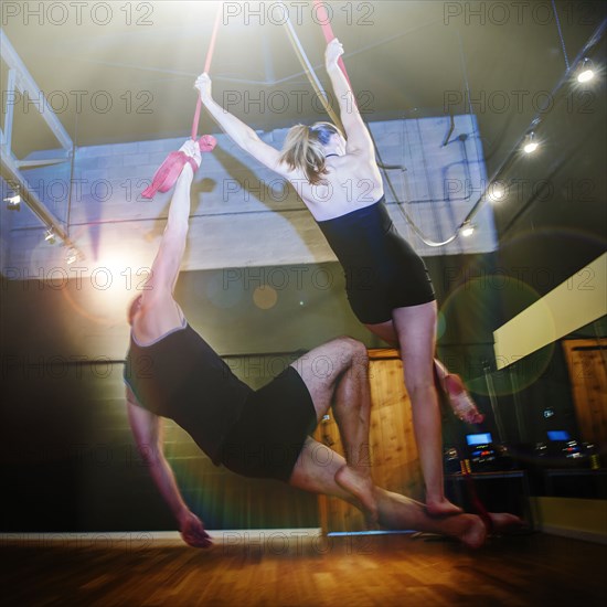 Caucasian acrobats hanging from ropes in studio
