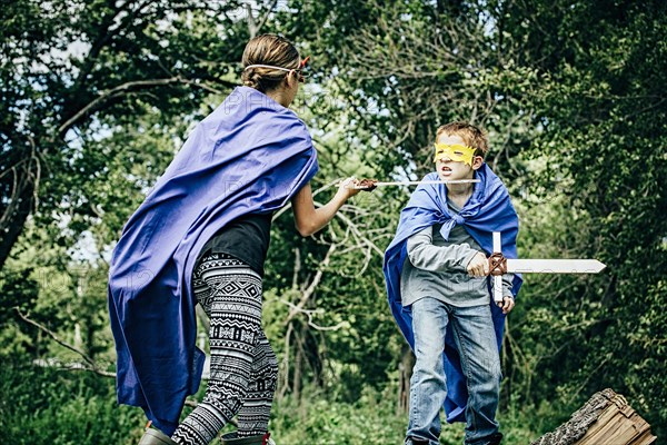 Caucasian children in costumes playing with swords