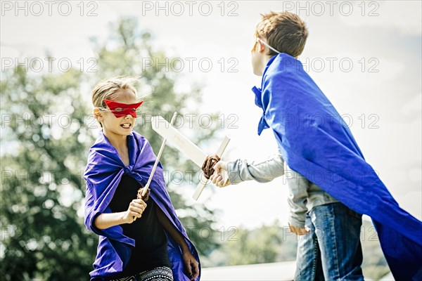 Caucasian children in costumes playing with swords
