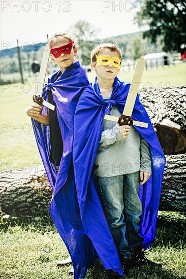 Caucasian children in costumes playing with swords