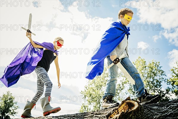 Caucasian children in costumes playing with swords