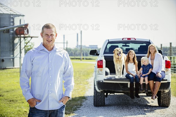 Caucasian man standing near family in truck bed