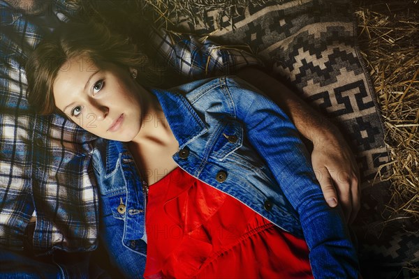 Caucasian woman laying with boyfriend on haystacks