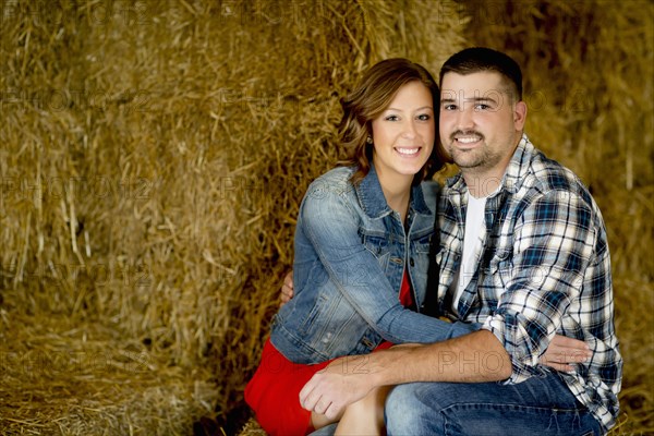 Caucasian couple hugging in haystacks