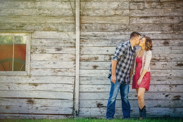 Caucasian couple kissing near wooden building