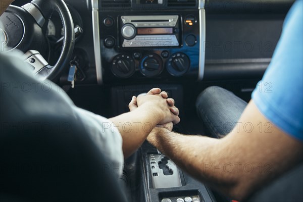 Caucasian couple holding hands in car