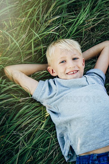 Caucasian boy laying in tall grass