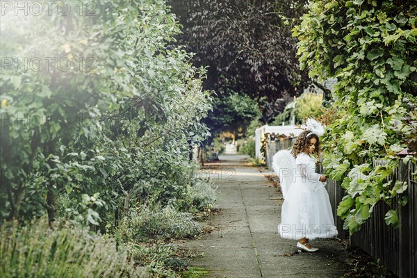 Mixed race girl wearing angel costume on sidewalk