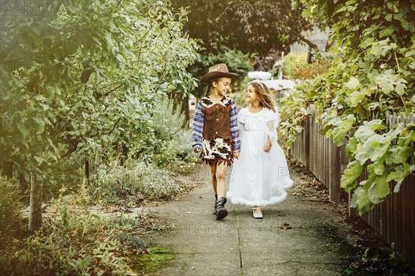 Sisters wearing Halloween costumes on sidewalk