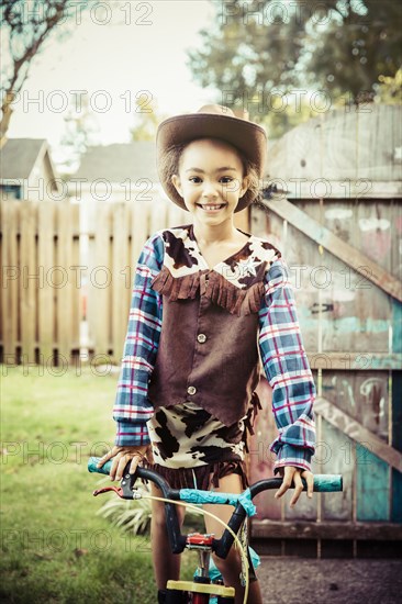 Mixed race girl wearing cowboy costume in backyard