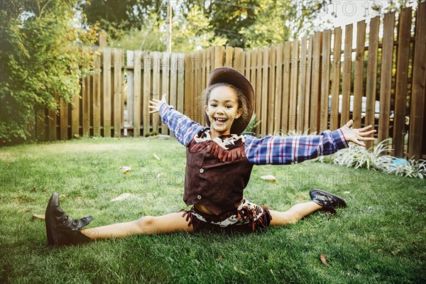 Mixed race girl wearing cowboy costume in backyard