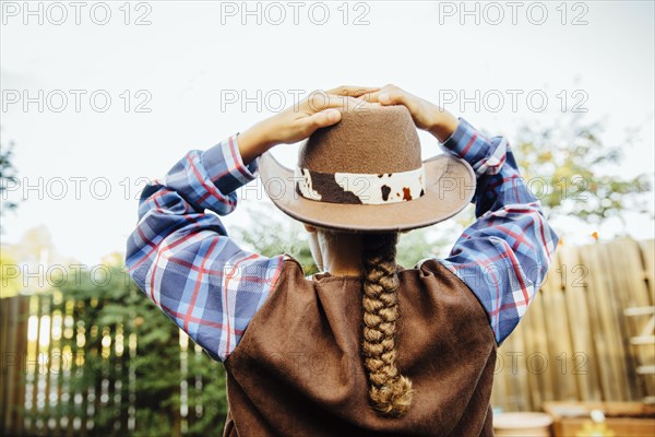 Mixed race girl wearing cowboy costume in backyard